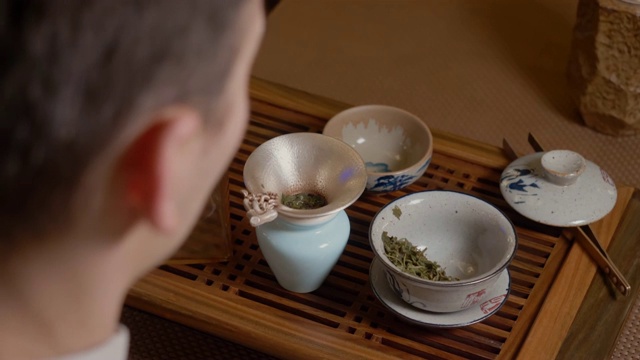 茶师将热水从茶壶倒入盖碗。热杯子里的蒸汽。绿茶