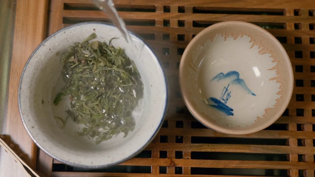 师傅将热水倒入盛有绿茶的碗中，盖上盖子，从上往下看