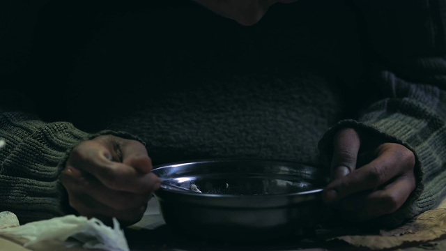 乞丐用颤抖的双手吃饭，为无家可归的穷人准备慈善晚宴
