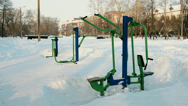 运动健身器材，覆盖着冰雪的冬季城市公园。