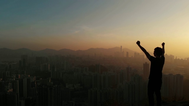 多丽向前的人站在山顶举起手臂庆祝。