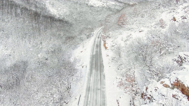 鸟瞰图冬季被雪覆盖的山路，驾驶汽车和卡车。无人机的顶视图。