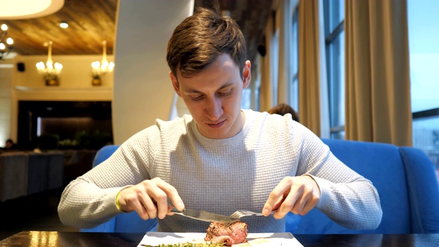 详情图-年轻人在餐馆里切牛肉，享受晚餐