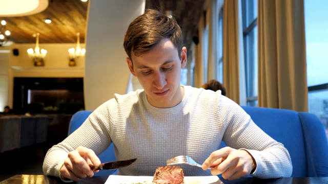 详情图-年轻人在餐馆里切牛肉，享受晚餐