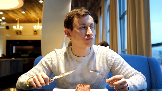 详情图-年轻人在餐馆里切牛肉，享受晚餐