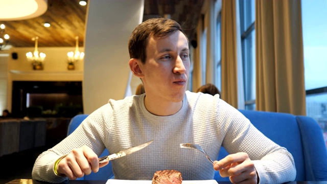 详情图-年轻人在餐馆里切牛肉，享受晚餐