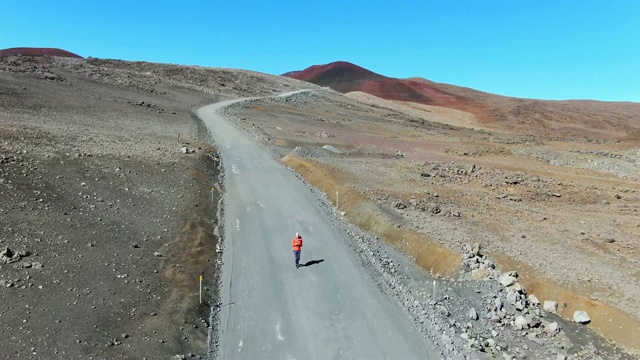 一架无人机拍摄到了一名年轻男性徒步旅行者在通往莫纳克亚火山山顶的砾石路上行走的惊人画面，莫纳克亚火山是美国夏威夷大岛上海拔4205米的最高山峰。