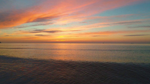 日出和热带海滩。海浪冲刷着沙子。