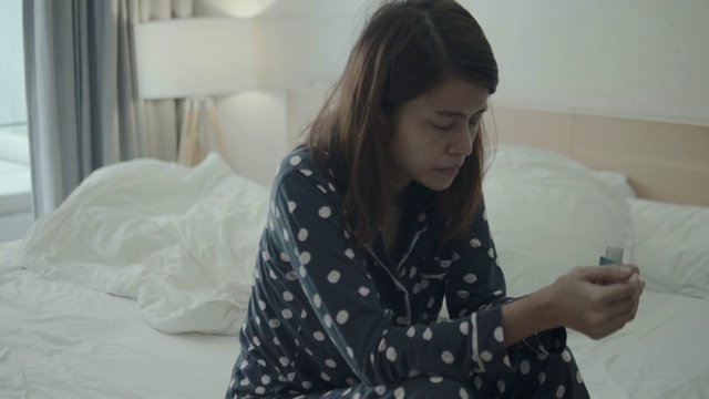年轻女子在家里的床上使用哮喘吸入器