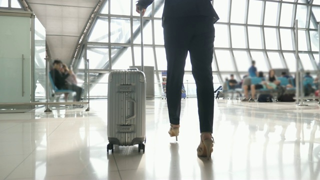 详情图-带着旅行袋在机场候机楼或地铁里行走的商务女性