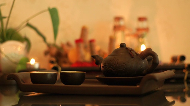 传统茶道用的木盘茶壶和茶杯。传统的茶壶为日本仪式上燃烧的蜡烛和香油背景。茶的成分