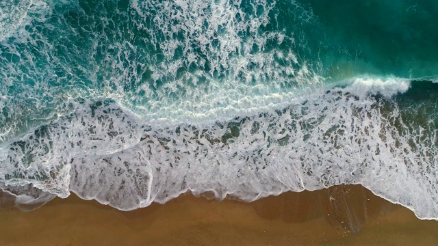 海浪或海浪拍岸。泡沫状的海浪翻滚着涌向沙滩。空中拍摄，4K