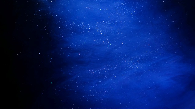闪光蓝色粒子背景。宇宙的蓝色尘埃与星星在黑色的背景。粒子的运动抽象。