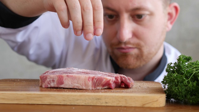厨师在厨房给牛肉放盐