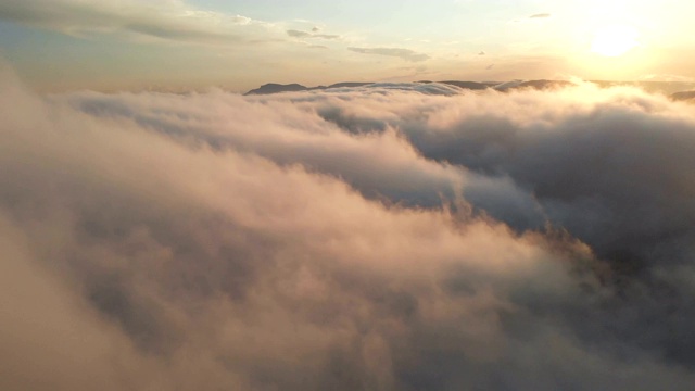 在黄昏或黎明飞过云层。飞行在粉红色的云在太阳鸟瞰图。