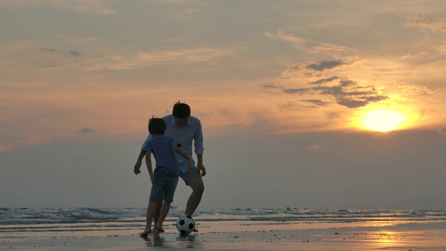 詳情圖-亞洲父親和兒子一起在沙灘上玩足球在夕陽的背景下。緩慢的運動。幸福的家庭的概念。