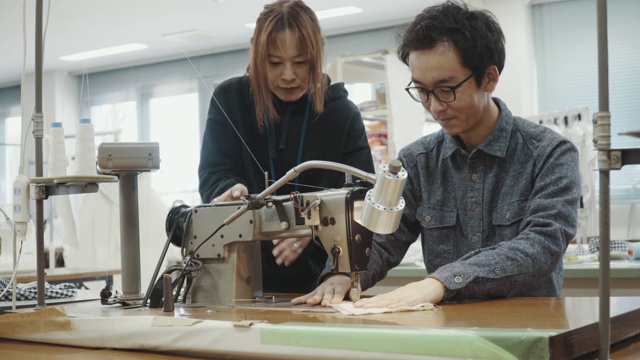 中镜头的两个中年设计专业人员一起工作在纺织制造工作室