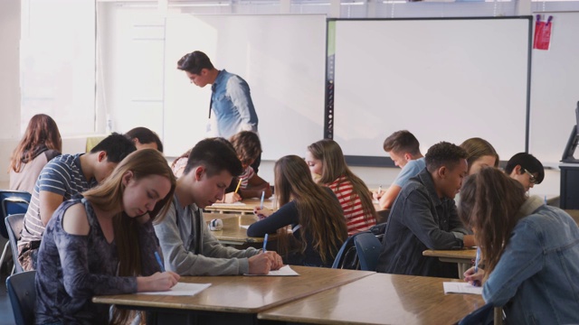 男高中老师在学生上课时在课桌之间走动