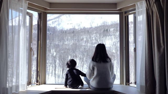 詳情圖-亞洲母親親吻和看雪窗可愛的小男孩在家里。