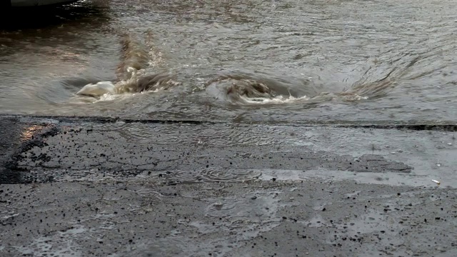 被洪水淹没的城市街道上的水流入暴雨排水沟。
