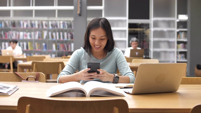 詳情圖-亞洲女學生使用智能手機進行圖書館教育，閱讀書籍和做筆記
