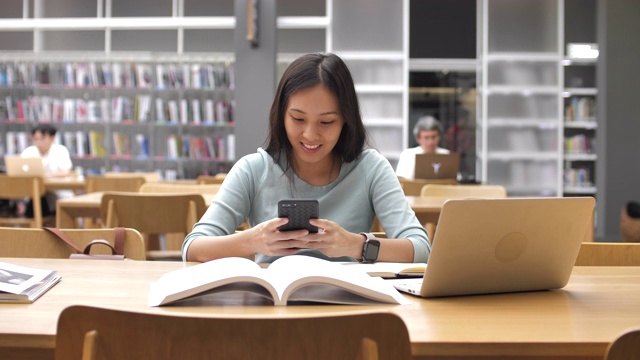詳情圖-亞洲女學生使用智能手機進行圖書館教育，閱讀書籍和做筆記