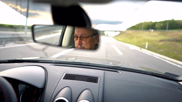 有经验的戴眼镜的老人在高速公路上开车