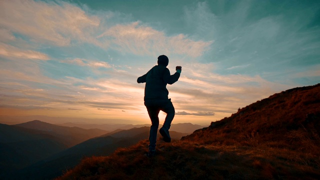 在美丽的夕阳下，一个人在山上跳跃。慢动作