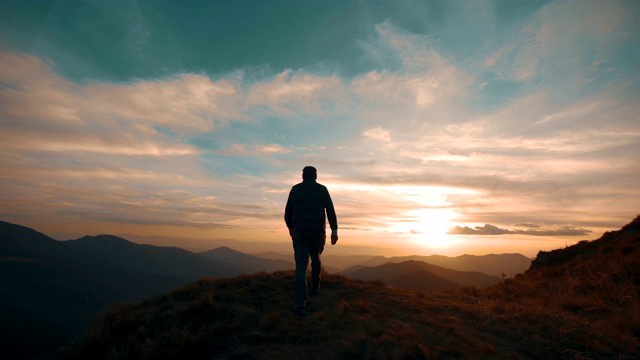 一个人站在山上，映衬着美丽的夕阳