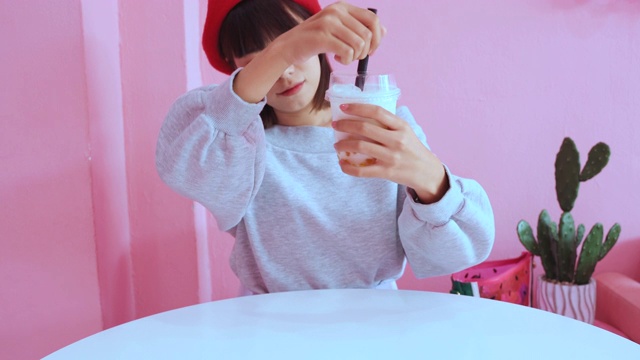 详情图-年轻的亚洲千禧一代女性在粉色柔和的咖啡馆喝冰珍珠奶茶