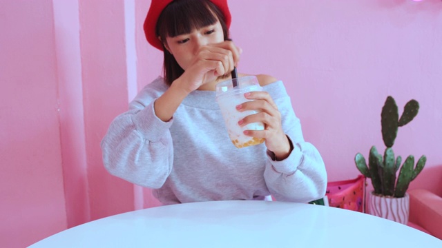 详情图-年轻的亚洲千禧一代女性在粉色柔和的咖啡馆喝冰珍珠奶茶