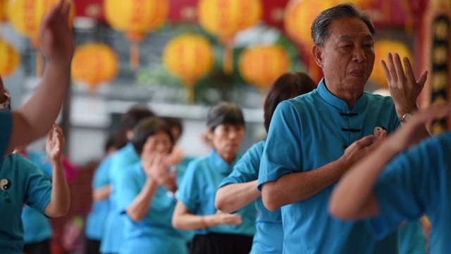 一名老人在一群人中间打着太极拳