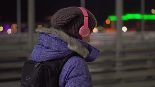 迷人的女人在夜间城镇的街道上使用手机