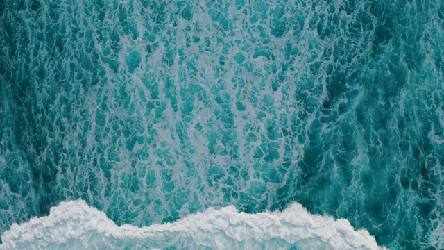 鸟瞰图，海浪沿着海岸拍打成泡沫