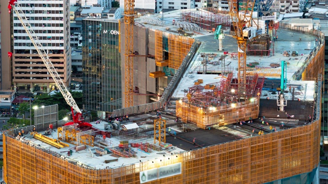 繁忙的工业建筑工地工人与起重机一起工作