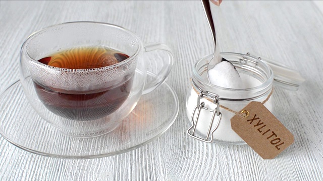 年轻女子在一杯茶中加入了代糖木糖醇，特写