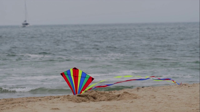 慢镜头彩虹风筝飞和降落在海洋海滩