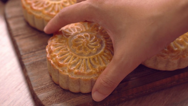 详情图-妇女把一个美丽的即食月饼放在一个木制托盘上下午茶，中秋节的习俗概念。