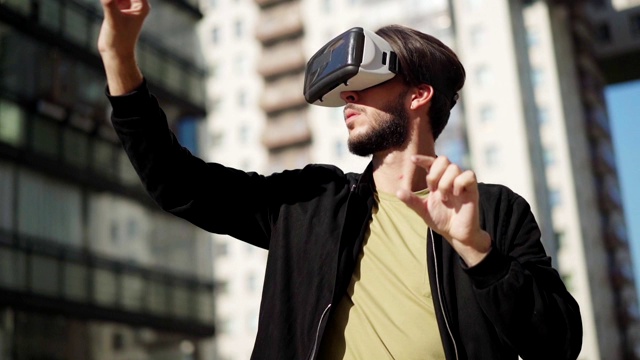 詳情圖-用慢鏡頭平移年輕男子戴著vr眼鏡站在城市街道的戶外，與虛擬現(xiàn)實(shí)中可視化的數(shù)據(jù)和信息一起工作