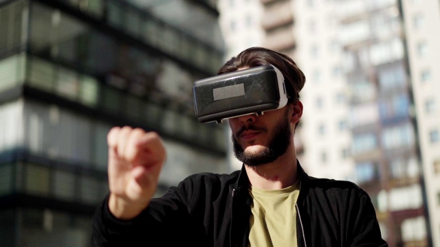 詳情圖-用慢鏡頭平移年輕男子戴著vr眼鏡站在城市街道的戶外，與虛擬現(xiàn)實(shí)中可視化的數(shù)據(jù)和信息一起工作