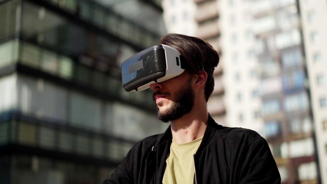詳情圖-用慢鏡頭平移年輕男子戴著vr眼鏡站在城市街道的戶外，與虛擬現(xiàn)實(shí)中可視化的數(shù)據(jù)和信息一起工作
