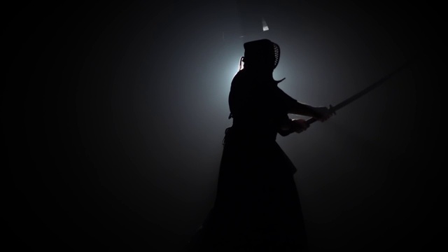 剪影剑道教练正在用武士刀练习武术。慢动作