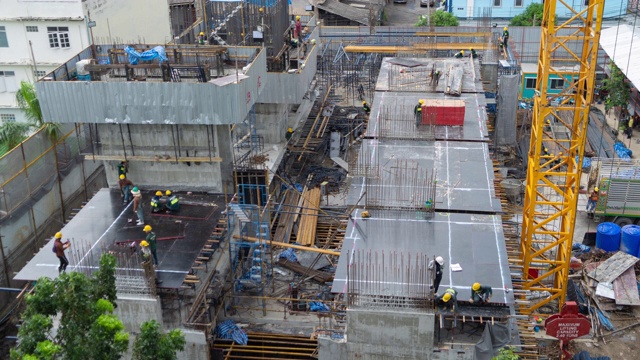 详情图-繁忙的工业建筑工地工人用起重机工作的鸟瞰图。中午发展高层建筑大楼俯视图。