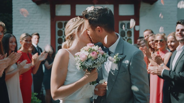 新婚夫妇在户外接吻时离开教堂