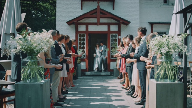 宾客们在教堂外向新婚夫妇投掷花瓣