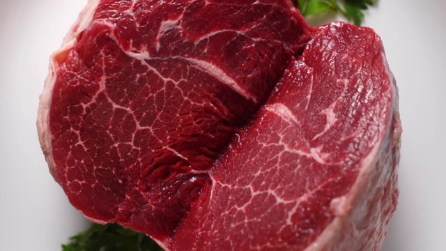生大理石肉切牛肉在盘子上旋转俯视图。