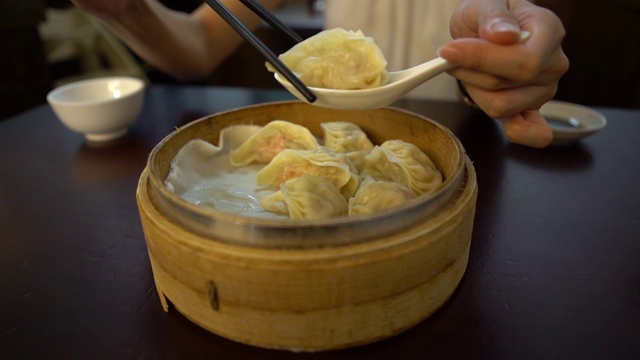 4K亚洲女人在餐厅吃饺子。传统的中国食物