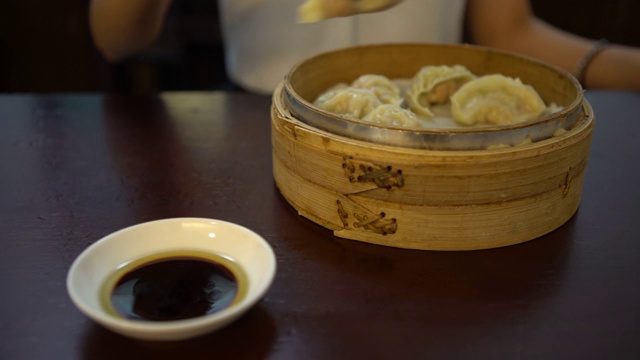 4K亚洲女人在餐厅吃饺子。传统的中国食物