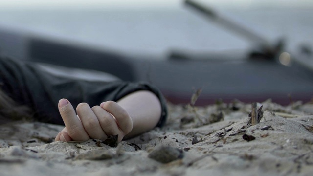 海难后，死女人的手躺在海岸上的特写，悲剧