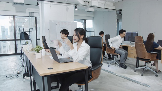 详情图-4K超高清:亚洲女员工在现代办公背景下使用笔记本电脑工作。